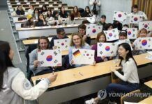 資料圖片：2月27日，在首爾明知大學人文校區，外國人留學生手繪韓國國旗。(圖片來源：韓聯社，明知大學供圖)